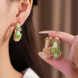 Primer plano detallado de pendientes en C vintage con cordón de colores y cuentas