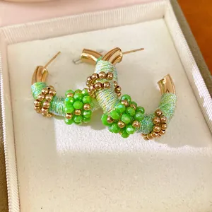 Primer plano de pendientes vintage en forma de C con envoltura de cuerda verde y perlas
