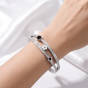 Elegant double-layered stainless steel bracelet featuring clover charms and pave crystals.