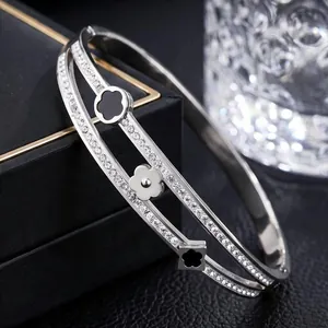 Close-up of elegant double-layer titanium steel bangle with clover charms and pavé stones