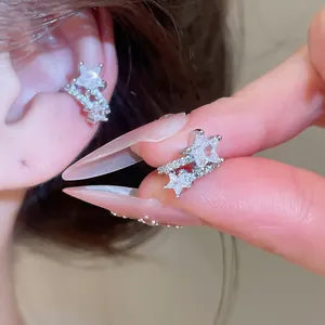 Macro detail of 18k gold plated star-shaped ear cuff set with clear sparkling zirconias