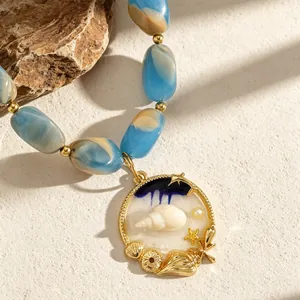 Detailed close-up view of blue white marbled resin beads and gold seashell pendant necklace