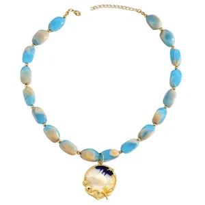 Detailed view of ocean-themed necklace with blue swirled resin beads and shell pendant