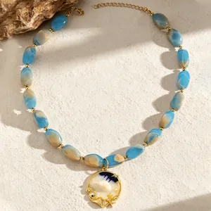 Detailed macro shot of blue marbled resin beads and gold seashell necklace pendant