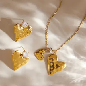 Close-up detail of a gold hammered heart necklace and matching earring set with crystals