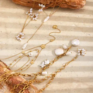 Detail von 18k vergoldeten Edelstahlketten mit Perlen und Blumenanhängern.