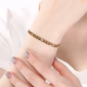 Vue rapprochée d'un bracelet gourmette Figaro minimaliste en acier doré au poignet.