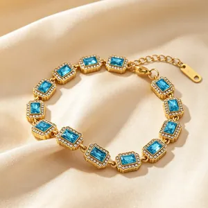 Nahaufnahme eines eleganten vergoldeten Armbands mit blauen Zirkonia auf Seidenhintergrund