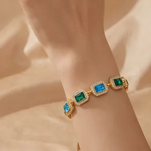 Detailaufnahme eines goldenen Vintage-Armbands mit grünen und blauen quadratischen Zirkonia.