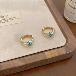 Detail view of gold-plated zircon flower hoop earrings in a cozy lifestyle setting
