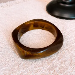 Vintage geometric resin bangle featuring amber-toned swirl pattern on woven fabric background