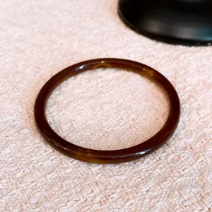 Close-up of a retro marbled resin bangle with amber-toned geometric patterns.