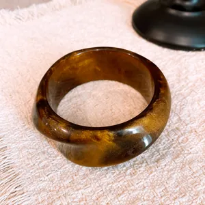 Macro view of retro marbled amber resin bangle featuring gold glitter shimmer and twisted shape