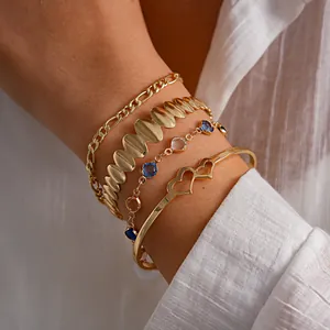 Primo piano di un elegante set di 4 bracciali in metallo dorato con un bracciale a cuore