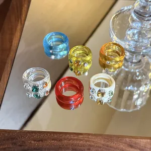 Close-up of colorful resin rings with sparkling rhinestone embellishments on a mirror