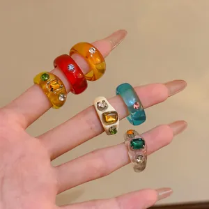 Detail of colorful resin rings with sparkling gemstones on manicured fingers