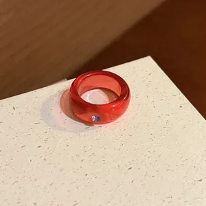 Detailed view of a minimalist translucent red resin ring with a small purple gemstone