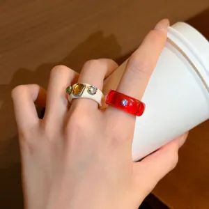 Detail view of colorful resin rings with inlaid sparkling crystals on hand