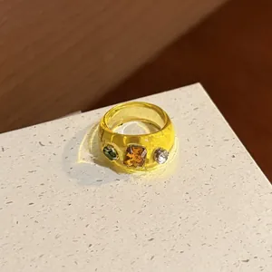 Macro detail of a chunky yellow resin ring with embedded colorful sparkling crystals