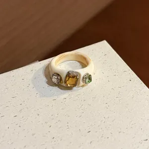 Detail showing a minimalist cream resin ring inlaid with three colorful crystals