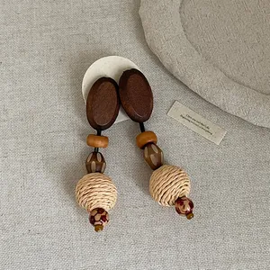 Close-up detail of vintage Bohemian style straw braided and wooden pendant drop earrings