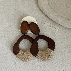 Macro detail of vintage bohemian earrings with dark wood and hand-woven straw texture