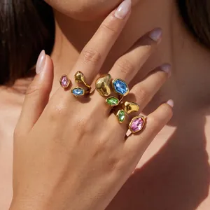 Detailansicht von bunten Glasringen an der Hand, eleganter Goldschmuck aus Edelstahl
