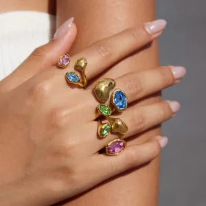 Detailansicht unregelmäßiger Goldringe mit bunten Glassteinen an der Hand eines Models