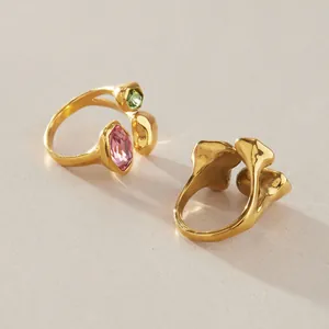 Makro-Detailansicht eines vergoldeten Edelstahlrings mit rosa und grünen Glassteinen