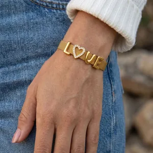 Detailansicht eines goldenen Armbands mit Kristallherz und LOVE-Anhängern