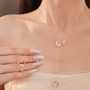 Detail view of 18k gold plated butterfly and round zircon necklaces on a model's neck