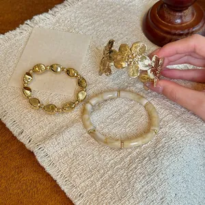 Vista dettagliata del set di bracciali in resina marmorizzata e polsini floreali oro