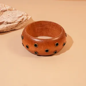 Vista detallada de un brazalete de resina marrón rojizo con detalles de ojales retro