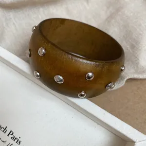 Vista dettagliata di un bracciale in resina ambrata con decorazioni a borchie d'argento