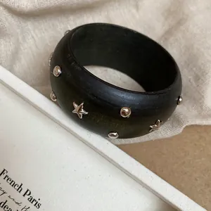 Dettaglio ravvicinato di un bracciale rigido in resina verde scuro con stelle e borchie argento