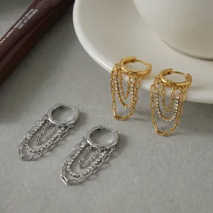 Primo piano di orecchini a cerchio oro e argento con eleganti catene di strass a strati.
