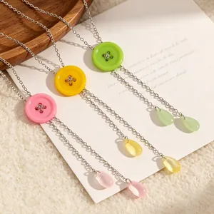 Detailopname van Y-vormige kettingen met macaronknoppen en pastelkleurige druppelhangers