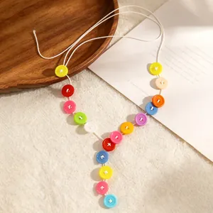 Detail van de macaron gekleurde knoop Y-vormige ketting op wit papier met houten bord