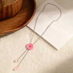 Detail van de roze macaron knoop en waterdruppel hangers aan een zilveren Y-ketting