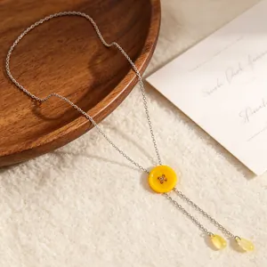 Detailweergave van de gele knoop en waterdruppelhangers aan een fijne Y-vormige ketting.