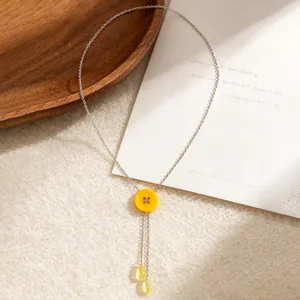 Detail van de Y-vormige halsketting met gele macaron knoop en waterdruppel hangers
