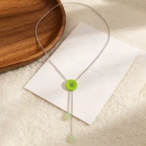 Detail van de Y-halsketting met groene knoop, kwastjes en druppelhangers