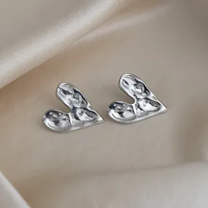 Vue détaillée de boucles d'oreilles cœur en argent avec texture martelée sur soie