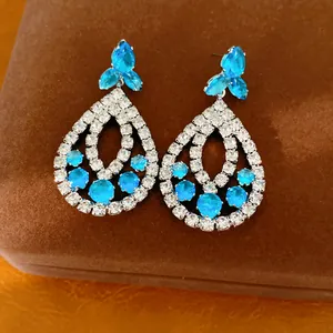 Nahaufnahme von luxuriösen Tropfenohrringen mit blauen Steinen und weißen Strasssteinen