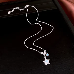Vista detallada de collar plateado con dijes de estrella y corazón azules en bandeja negra.