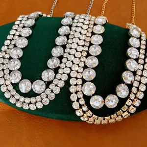 Close-up view of multi-layered sparkling rhinestone necklaces on a green velvet stand