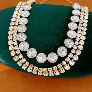 Macro detail shot showing multi-layered gold-tone necklace with sparkling round crystals