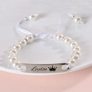 Detailed view of personalized stainless steel plate on 8mm white faux pearl baby bracelet