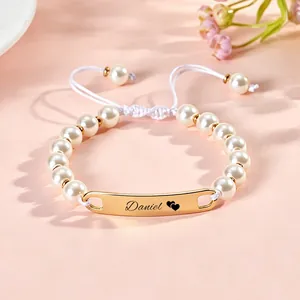 Close-up of customized gold bar pearl bracelet with engraved name Daniel and hearts