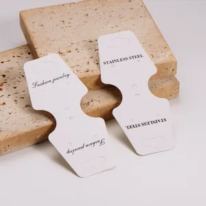 Close-up of white foldable jewelry display cards on textured stone prop